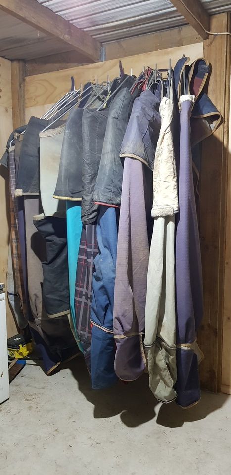 Horse covers on rack in stable